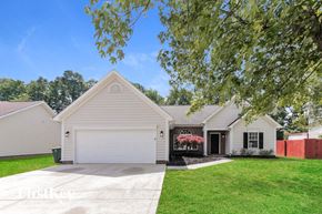 Charlotte house for rent - A house with a garage and a driveway is surrounded by greenery.