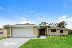 Lehigh Acres house for rent - a beige house with a garage door and a lawn