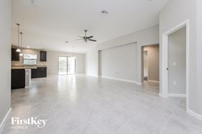 Lehigh Acres house for rent - an empty living room and kitchen with a ceiling fan