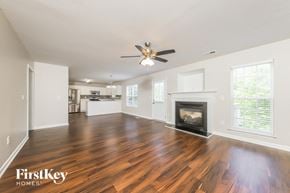 Winston-Salem house for rent - an empty living room with a fireplace and a ceiling fan