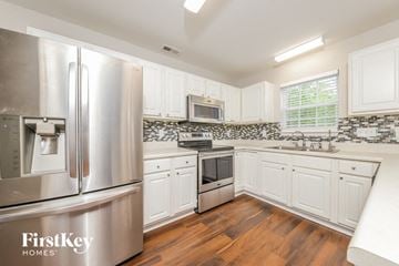 Winston-Salem house for rent - a kitchen with white cabinets and stainless steel appliances