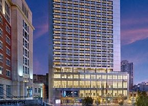New Brunswick apartment for rent - A tall building with many windows is lit up at dusk.