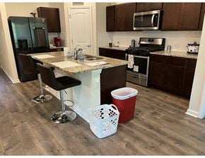 Youngsville house for rent - a kitchen with a counter and a bar with chairs and a trash can