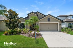 Riverview house for rent - a beige house with a garage door and palm trees