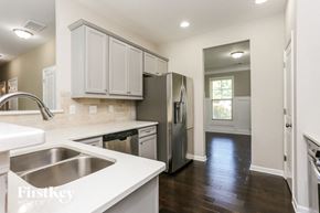 Cumming house for rent - a kitchen with white cabinets and a stainless steel refrigerator and sink