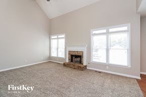 Dallas house for rent - A spacious room with a fireplace and two windows.