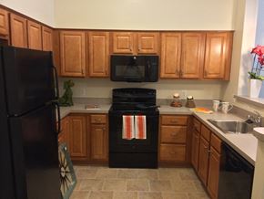 Baltimore apartment for rent - a kitchen with black appliances and wooden cabinets