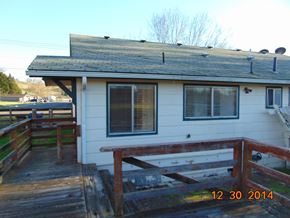 Eagle Point apartment for rent - A house with a wooden deck and a roof with vents.