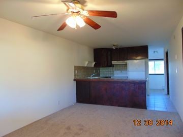 Eagle Point apartment for rent - A room with a ceiling fan and a kitchen area in the background.