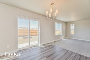 Colorado Springs house for rent - A spacious room with a chandelier and a view of a fence and trees outside the window.