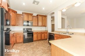 Phoenix house for rent - a kitchen with wooden cabinets and black appliances