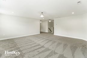 Colfax house for rent - A spacious room with a carpeted floor and a door in the background.