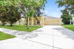 Apopka house for rent - a white driveway in front of a yellow house