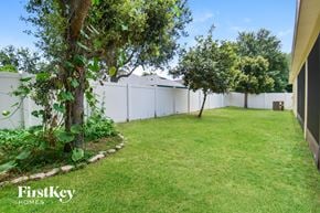 Apopka house for rent - a backyard with grass and trees and a white fence