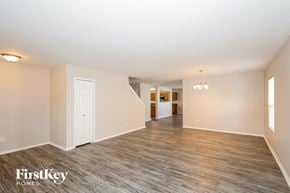 Gastonia house for rent - A spacious room with wood flooring and a staircase leading to another room.