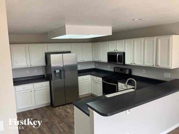 Fountain house for rent - a kitchen with white cabinets and a stainless steel refrigerator