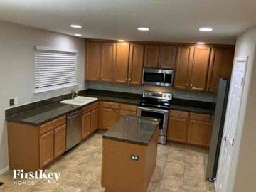 Fountain house for rent - A kitchen with wooden cabinets and a black countertop.