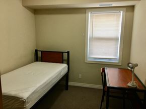 Waterloo apartment for rent - a small bedroom with a bed and a desk and a window
