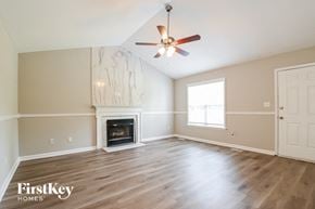 Willow Spring house for rent - A spacious room with a fireplace and a ceiling fan.