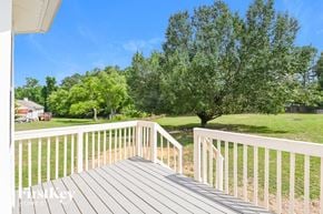 Willow Spring house for rent - A wooden deck with a white railing overlooks a grassy area.