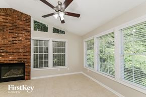 High Point house for rent - an empty living room with a brick fireplace and a ceiling fan