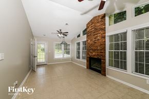 High Point house for rent - an empty living room with a brick fireplace and a ceiling fan