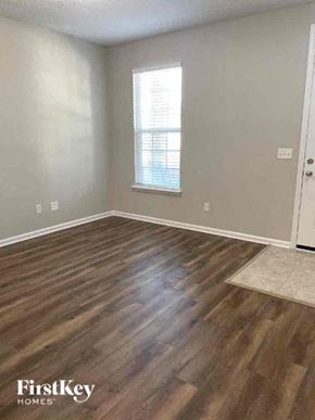Jacksonville house for rent - an empty living room with wood floors and a window