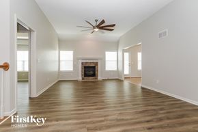 Kansas City house for rent - A spacious room with a fireplace and a ceiling fan.