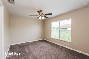 Lehigh Acres house for rent - a bedroom with a ceiling fan and a window