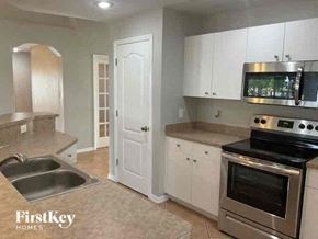 Cape Coral house for rent - a kitchen with stainless steel appliances and white cabinets