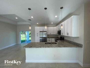 Cape Coral house for rent - a kitchen with white cabinets and a granite counter top