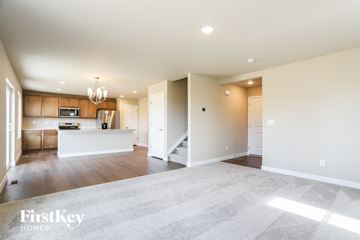 Colorado Springs house for rent - A spacious living room with a kitchen in the background and a carpet on the floor.