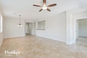 Tucson house for rent - A spacious room with a ceiling fan and a hanging light fixture.