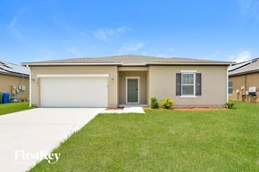 Winter Haven house for rent - A beige house with a garage door and a red brick pathway leading to the front door.