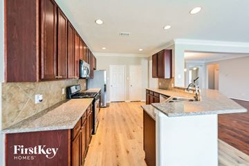 Katy house for rent - A kitchen with wooden cabinets and a countertop that says FirstKey Homes.