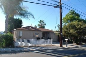 Vista apartment for rent - A house with a white picket fence is surrounded by trees and utility poles.