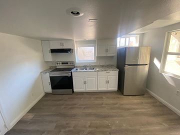 Vista apartment for rent - A kitchen with white cabinets and a black fridge.