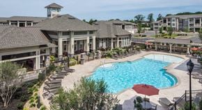 Mooresville apartment for rent - a large swimming pool with lounge chairs in front of a building