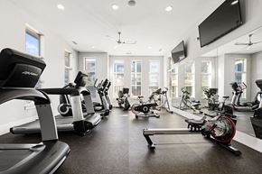 Mooresville apartment for rent - A spacious gym with treadmills, elliptical machines, and a television.