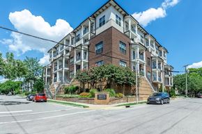 Nashville apartment for rent - A street view of a multi-story building with cars parked in front.
