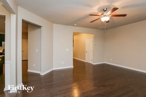 Lawrenceville house for rent - A spacious room with a ceiling fan and wooden flooring.