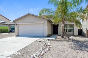 Marana house for rent - A house with a white garage door and a palm tree in front.