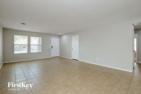 Marana house for rent - A spacious room with beige tiled flooring and white walls, with a door on the right and a window on the left.
