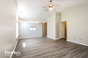 Indianapolis house for rent - A spacious room with a ceiling fan and light fixture, and a doorway leading to another room.