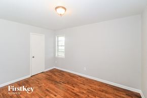 Collierville house for rent - a bedroom with wood flooring and white walls and a white door