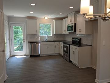 Raleigh house for rent - A kitchen with white cabinets and a black countertop.