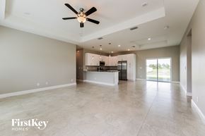 Cape Coral house for rent - A spacious living room with a ceiling fan and a kitchen in the background.