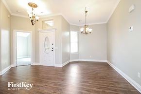 Yukon house for rent - A large empty room with a chandelier and a door leading to a balcony.