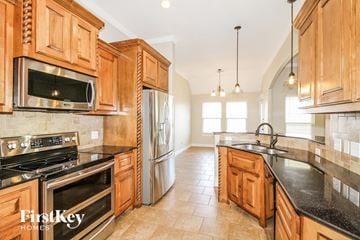 Yukon house for rent - A kitchen with wooden cabinets and a black countertop.