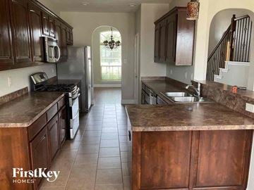 Fort Worth house for rent - a large kitchen with wooden cabinets and a stainless steel refrigerator
